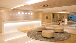 Una moderna zona de recepción con un mostrador, tres áreas de estar circulares y un suelo de madera.