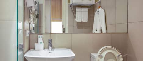 Un baño con cabina de ducha de vidrio, un lavabo, un inodoro y un espejo.