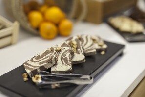 Une assiette de desserts avec des motifs tourbillonnants de chocolat et de crème, des noix et un plateau noir posé sur un comptoir blanc.
