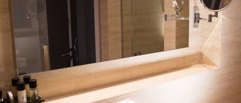 A modern bathroom with a large mirror, a sink, and a glass shower enclosure.