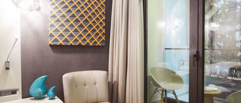 A modern living room with a sofa, a glass door leading to a balcony, and a decorative wall piece.