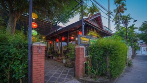 A traditional building with a tiled entrance, surrounded by greenery and palm trees. - Countryside Moon Homestay (Da Nang)