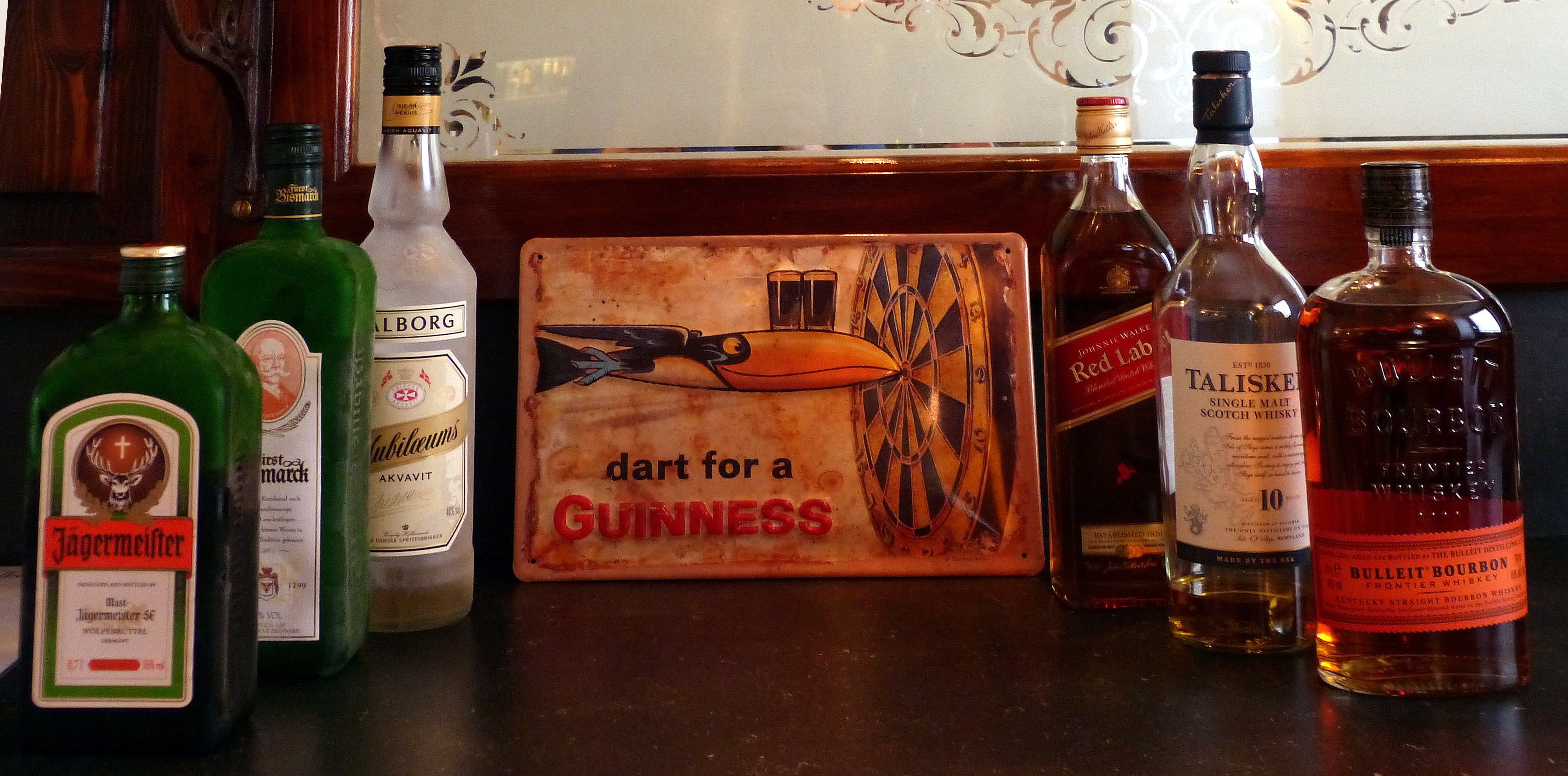 Una barra con varias botellas de licores, incluyendo Jagermeister, Guinness, Talisker y Bulleit Bourbon.