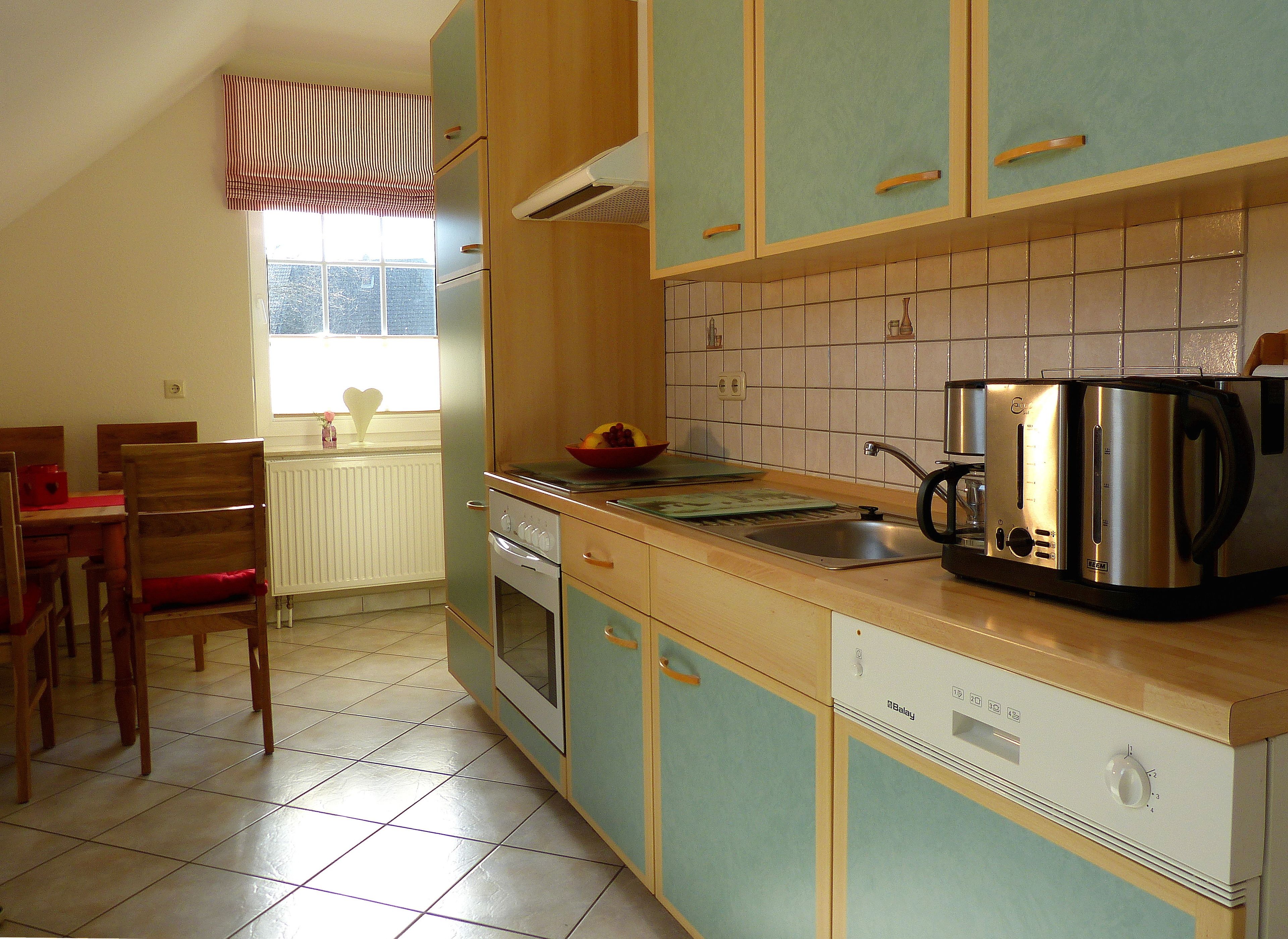 A kitchen with wooden cabinets, a sink, a stove, and a coffee maker.