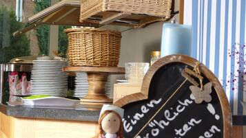 A kitchen counter with wicker baskets, a chalkboard with a message, and a doll.