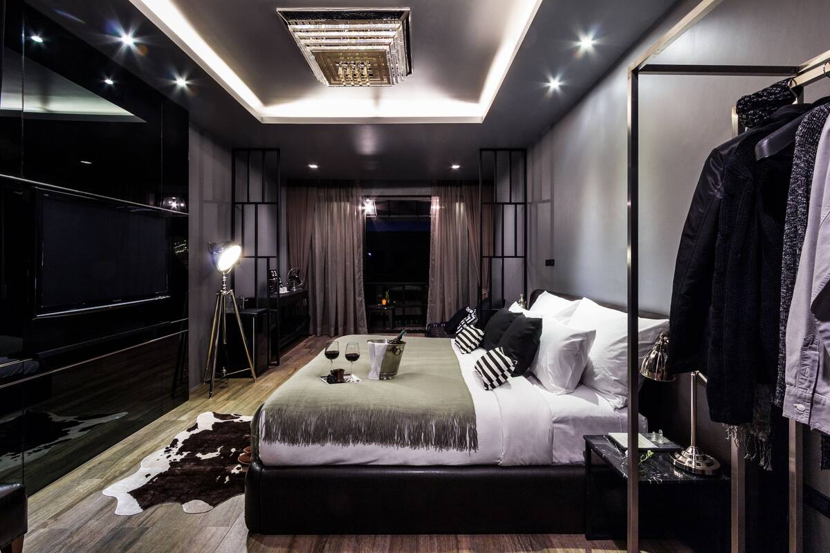 Une chambre moderne dotée d’un grand lit, d’un téléviseur à écran plat, d’un piano et d’un coin repas avec une table et des chaises.