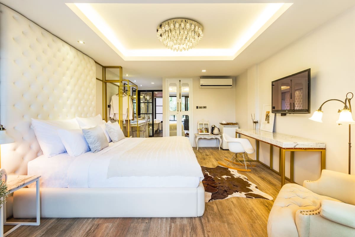 Une chambre moderne avec un grand lit, un lustre, un bureau et un miroir.