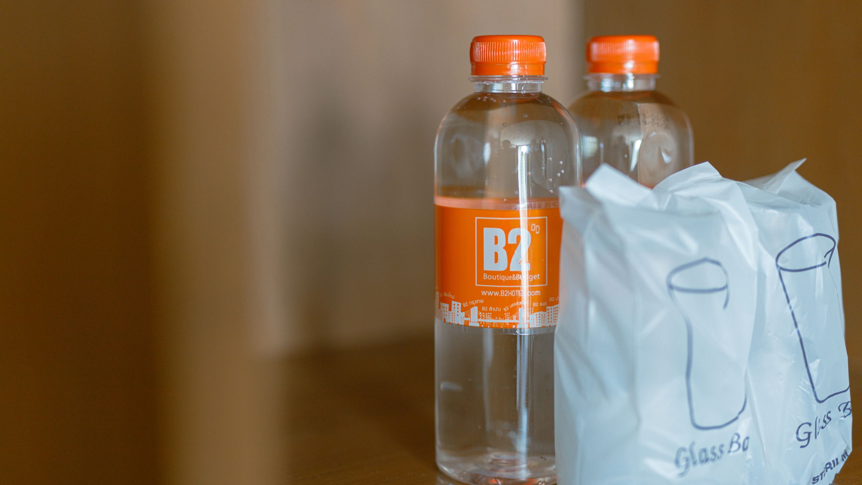 Two clear plastic bottles with orange caps and a white paper bag with text on it.