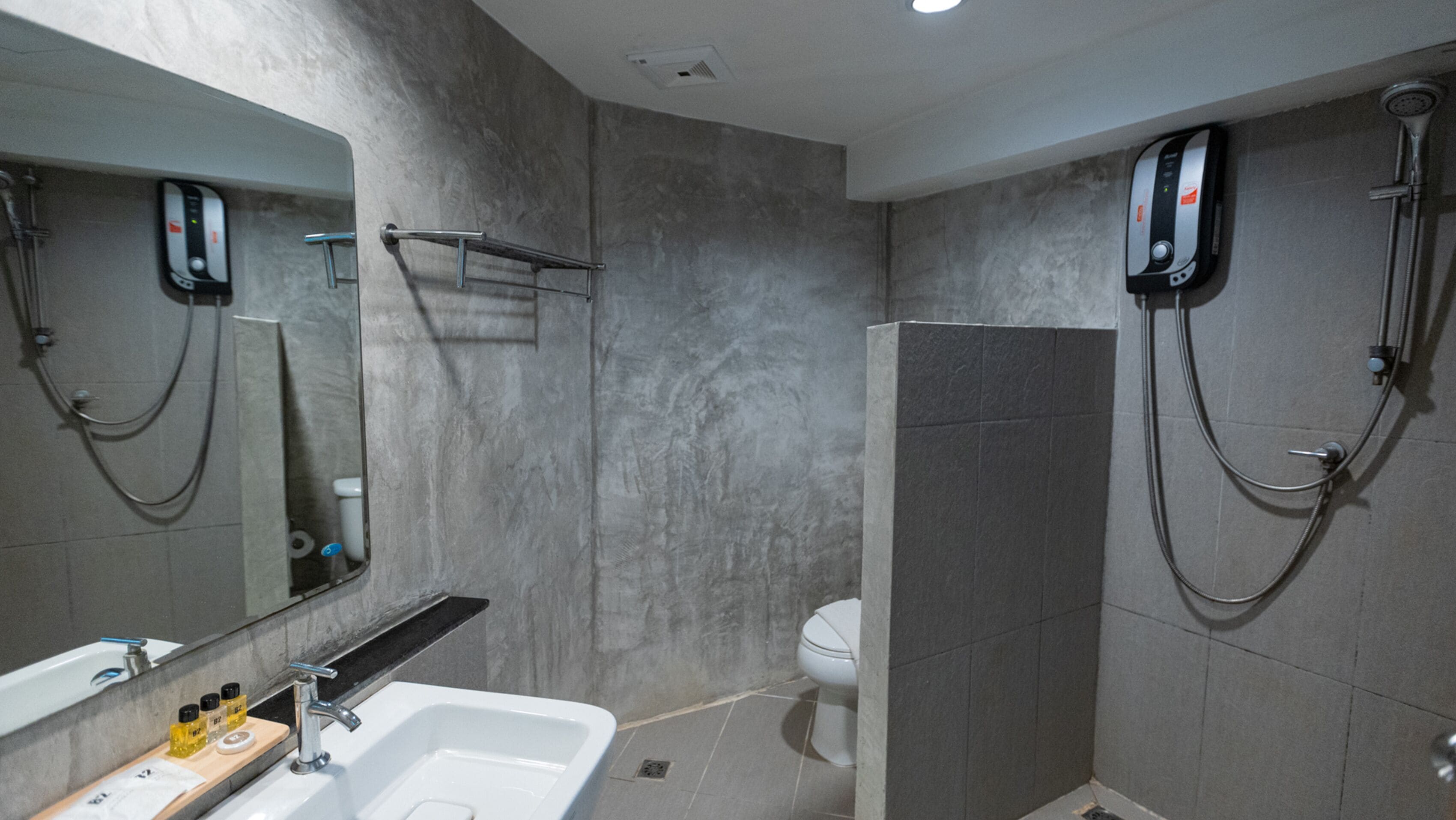 Un bagno moderno con uno specchio grande, un lavandino, un water e una doccia.