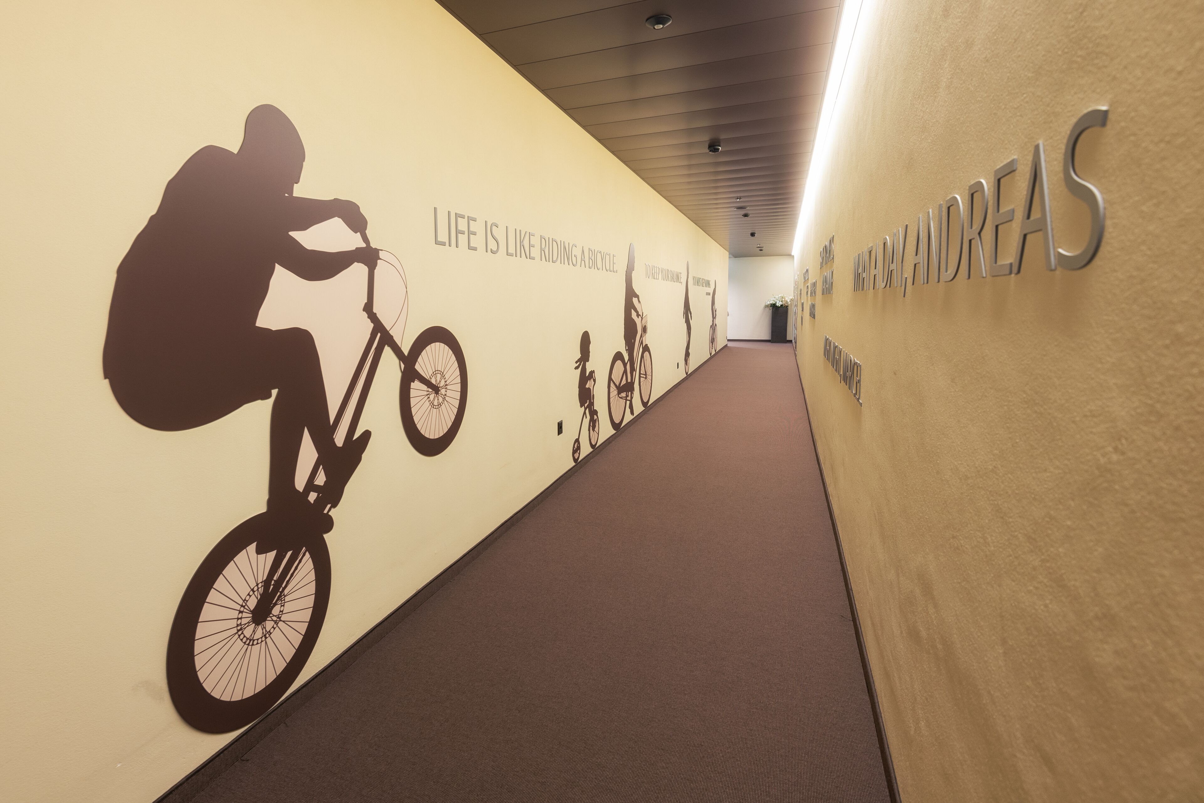 A hallway with a wall mural of a cyclist and the text "LIFE IS LIKE RIDING A BICYCLE."