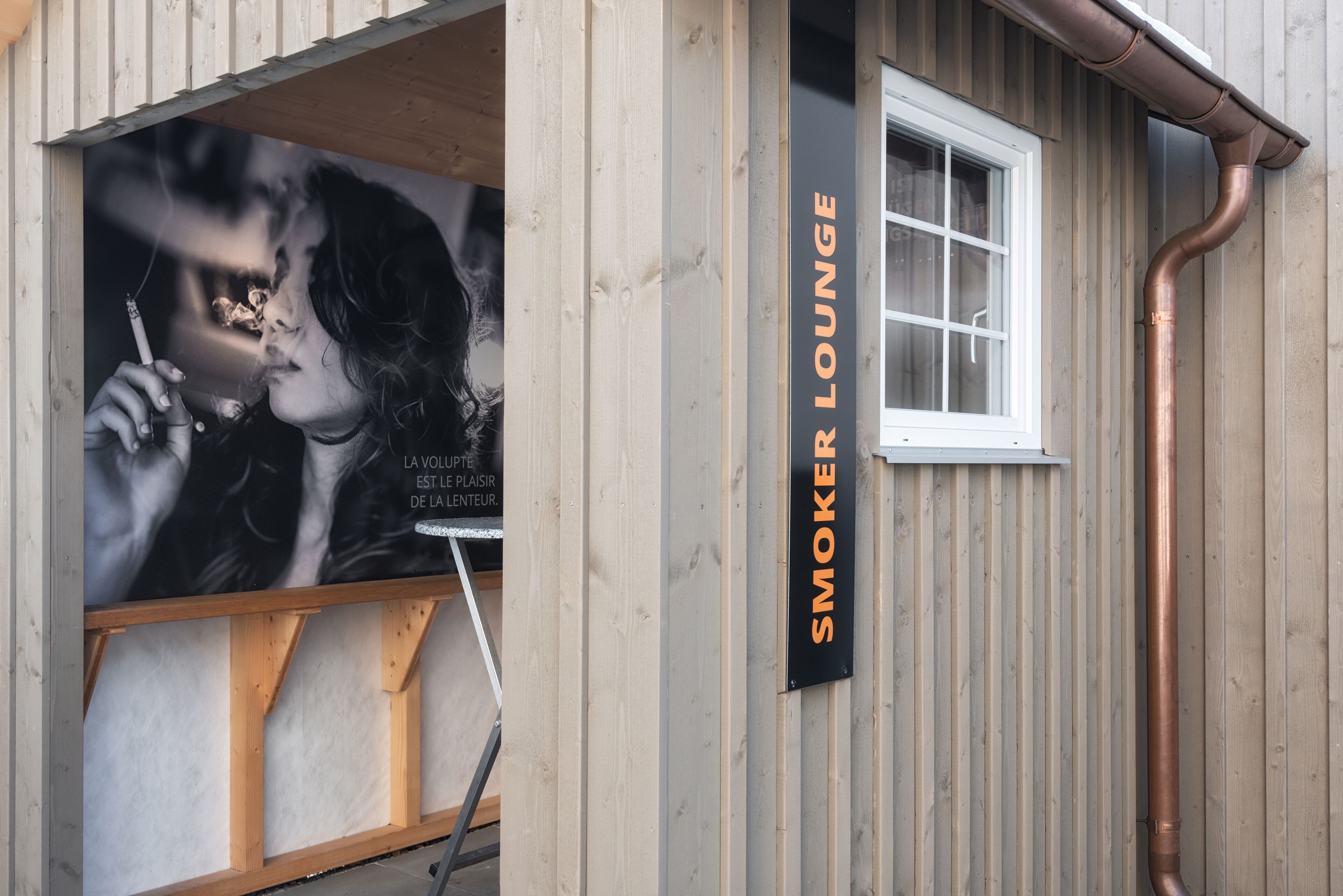 A building with a sign reading "SMOKER LOUNGE" and a poster of a woman smoking.