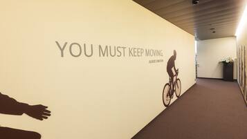 A hallway with a motivational quote on the wall, a cyclist silhouette, and a potted plant.