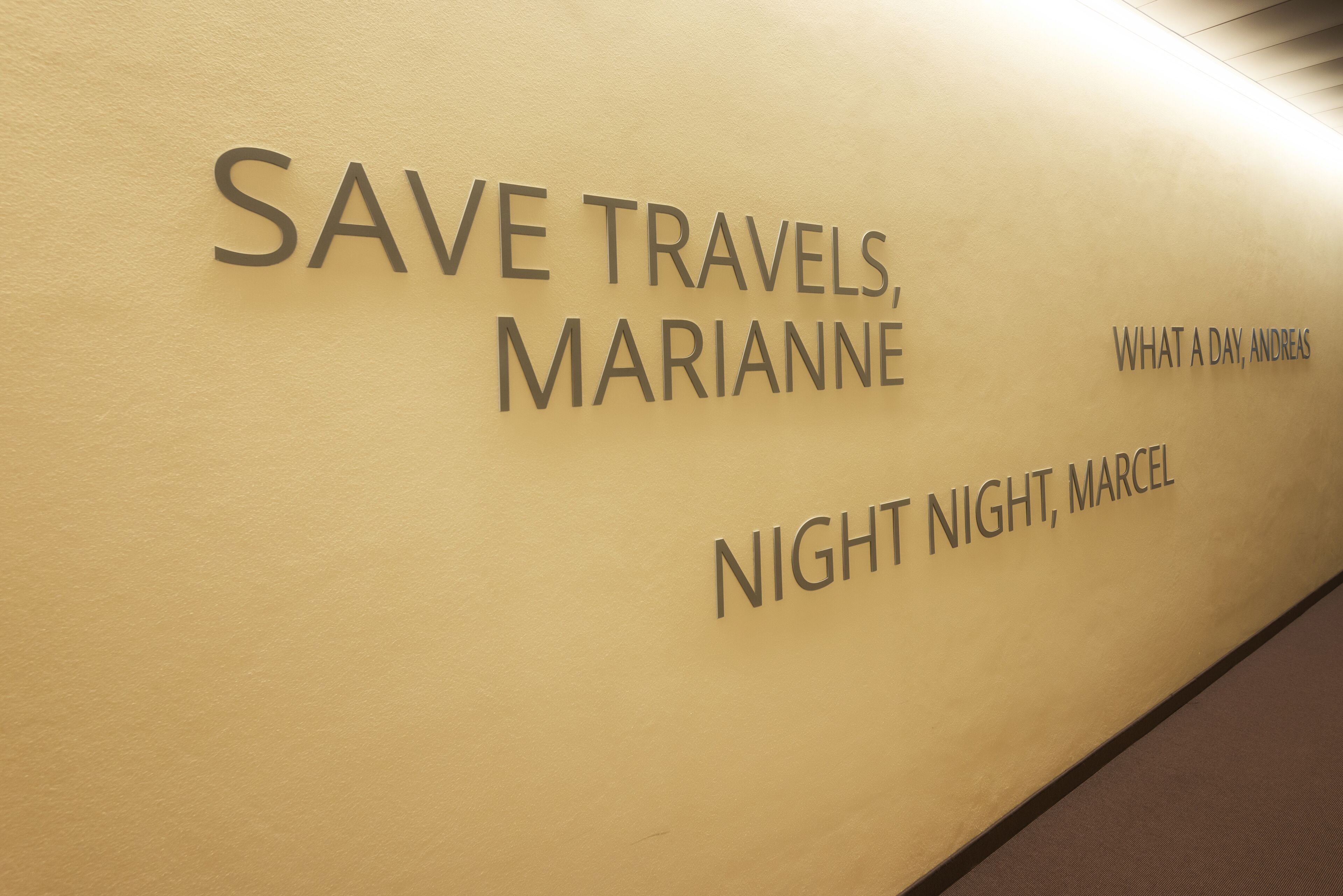 A wall with the text "SAVE TRAVELS, MARIANNNE" and "NIGHT NIGHT, MARCEL".