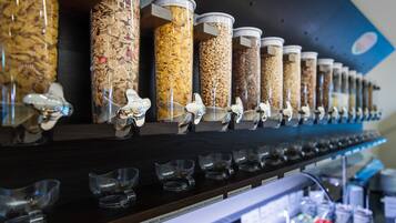 Een etalage met verschillende bakken vol snacks en een rij lege glazen eronder.