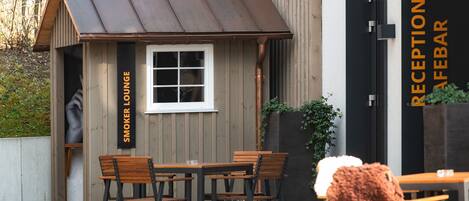 A reception bar with a wooden exterior and a small lounge area with tables and chairs.