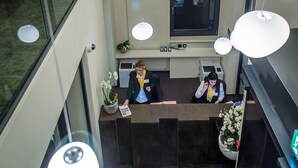 A reception area with multiple hanging spherical lights, a reception desk, and a large window.