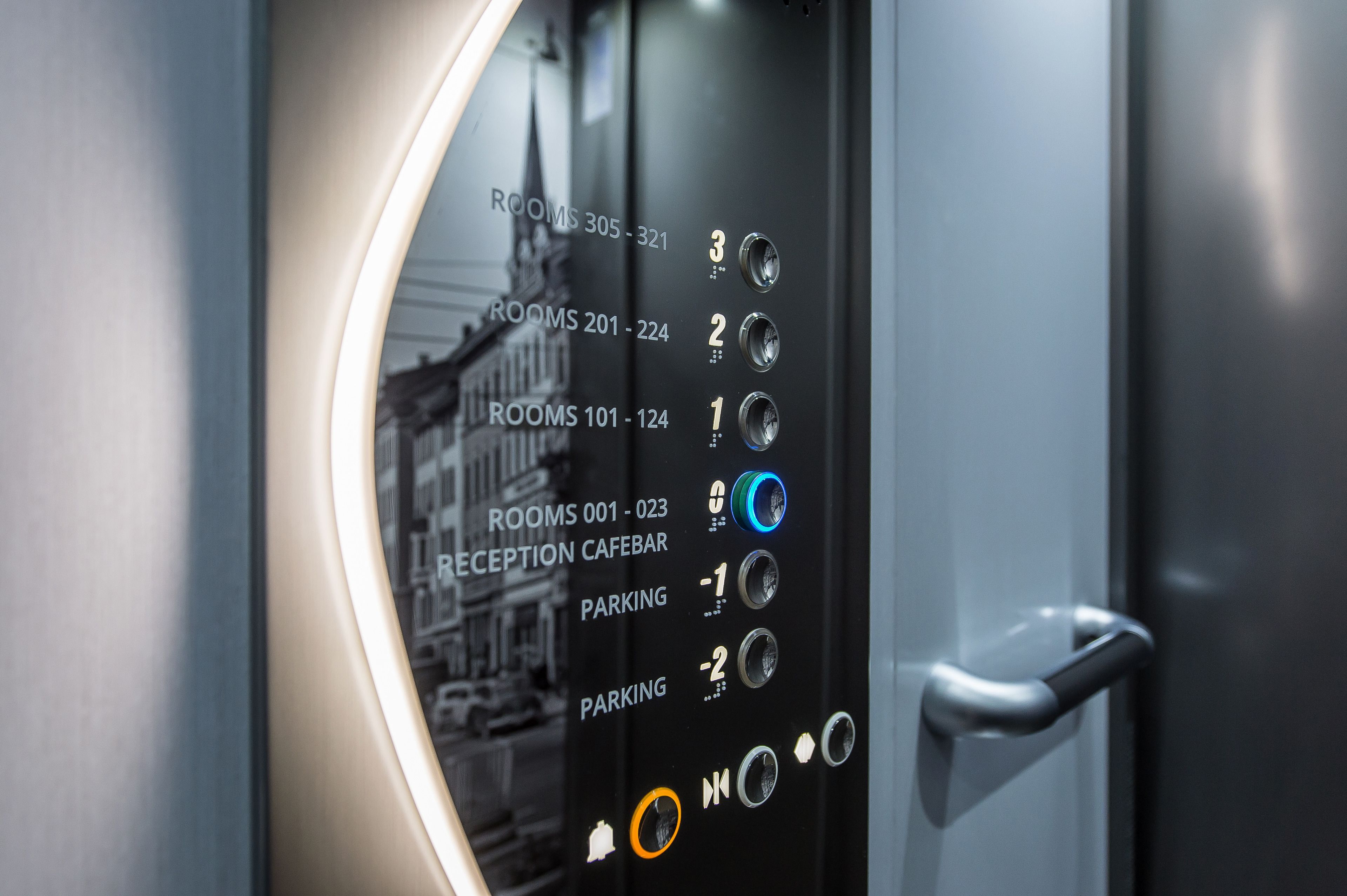 Painel de controlo de elevador de hotel, com números de quartos e balcão de receção.