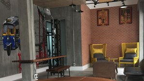 A modern interior with a round wooden table, yellow chairs, and a brick wall with artwork. - Bed@Town Hostel (Bangkok)