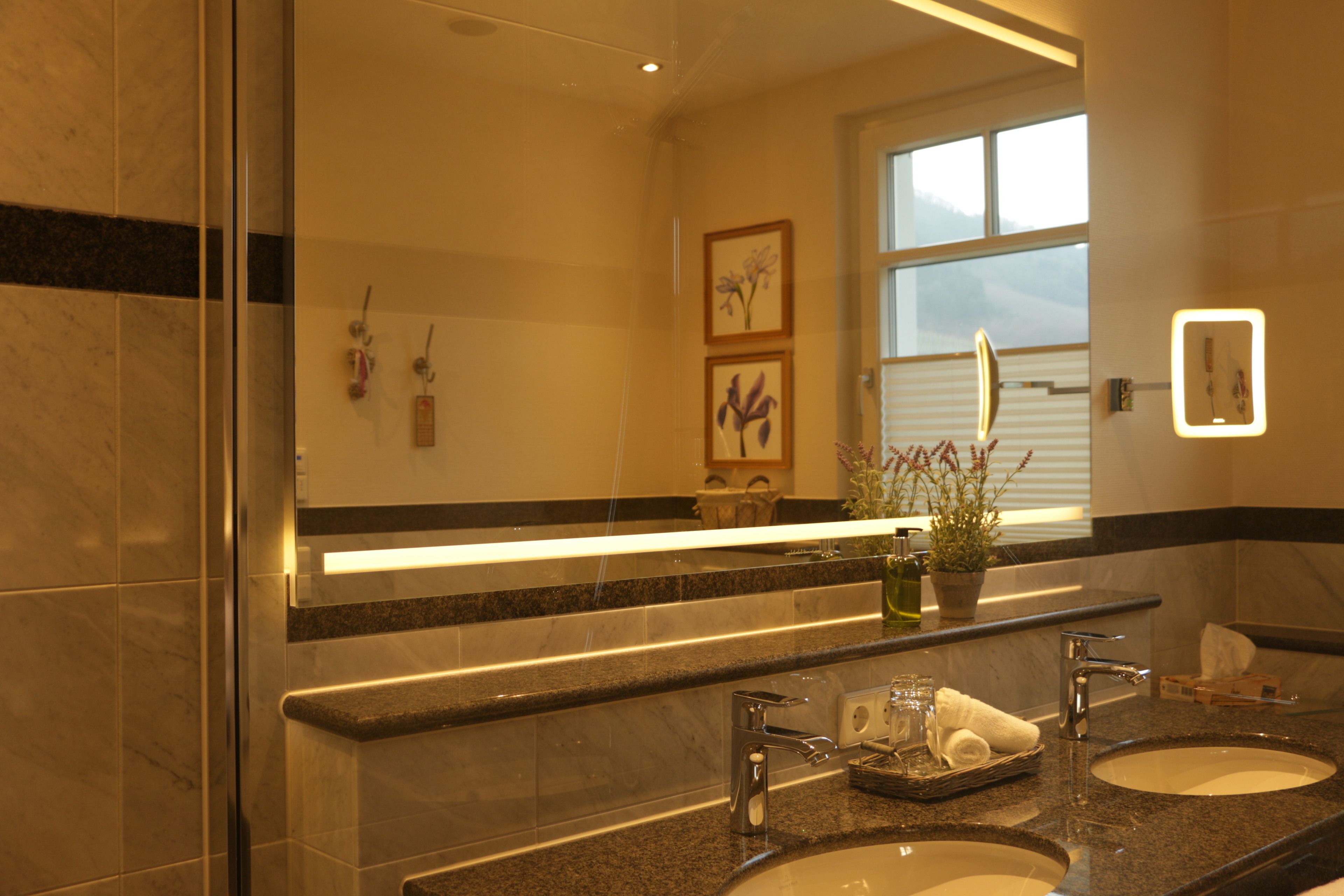 Un baño moderno con dos lavamanos, un espejo grande y un ventanal que proporciona luz natural.