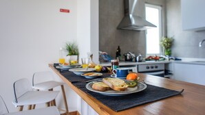 Una cocina moderna con una mesa de comedor lista para el desayuno, incluyendo tostadas, fruta y una taza de café.