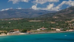 A coastal landscape with a view of mountains in the background, a beach, and scattered buildings. - Kyniska Hotel (Monemvasia)