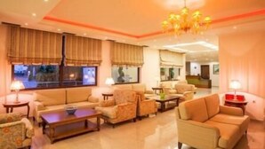 A spacious living room with a sofa set, a coffee table, and a TV. - Kyniska Hotel (Monemvasia)
