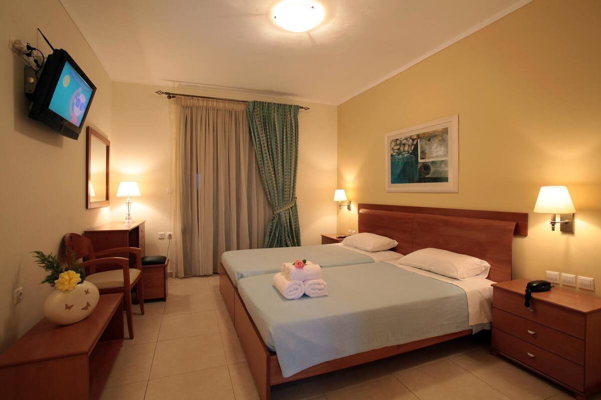 Une chambre d’hôtel avec un lit, des tables de chevet, une télévision et un tableau au mur.