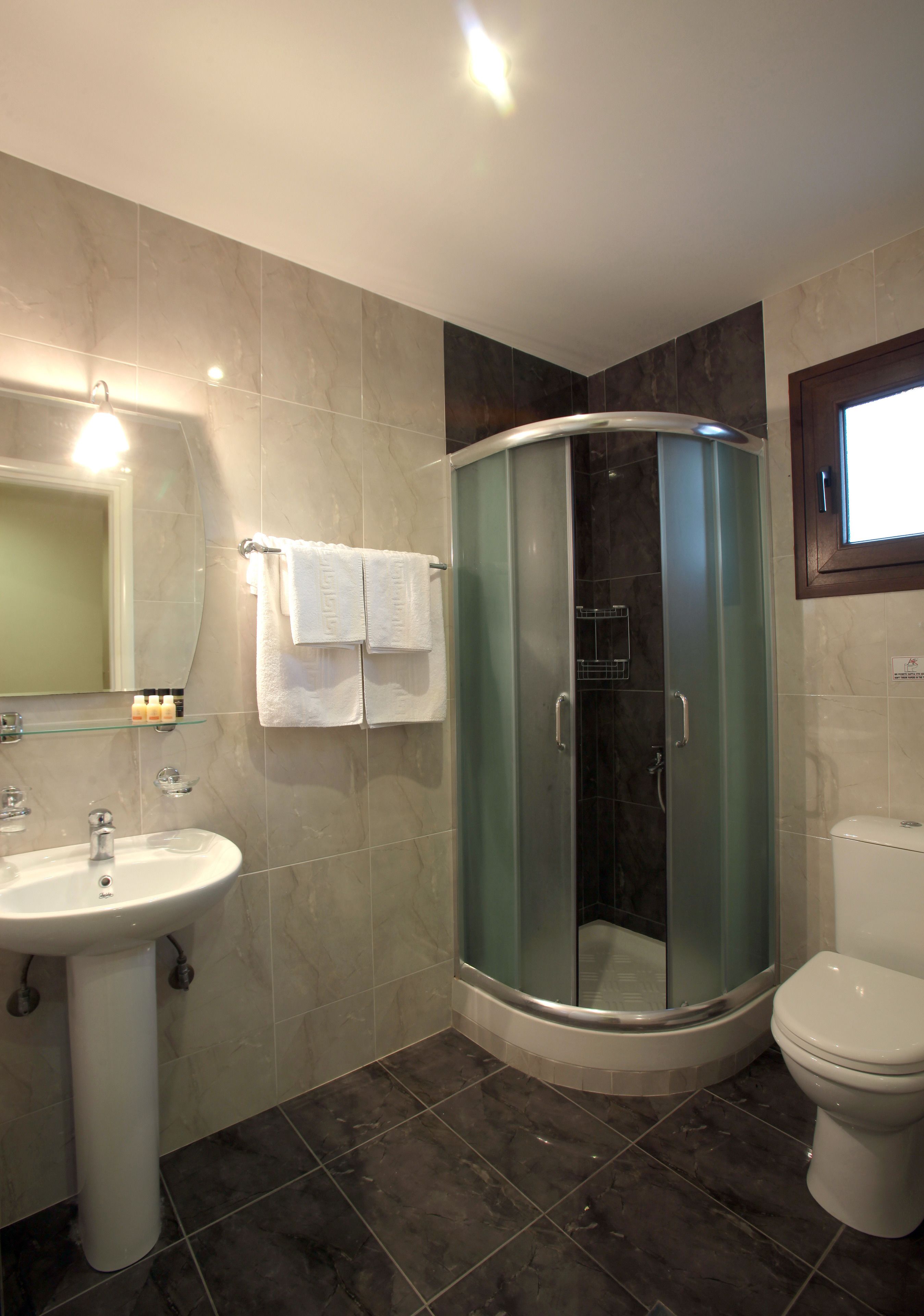 A bathroom with a glass-enclosed shower, a sink, and a toilet.