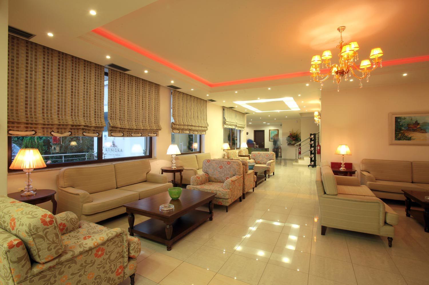 A spacious living room with a sofa, armchairs, a coffee table, and a chandelier.