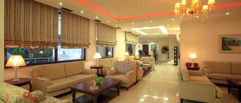 A spacious living room with a sofa, armchairs, a coffee table, and a chandelier.