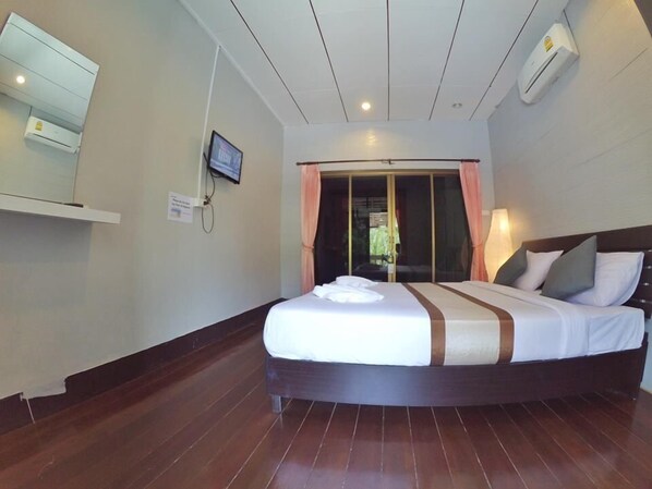 Quarto de hotel com uma cama grande, televisão fixada na parede e aparelho de ar condicionado.