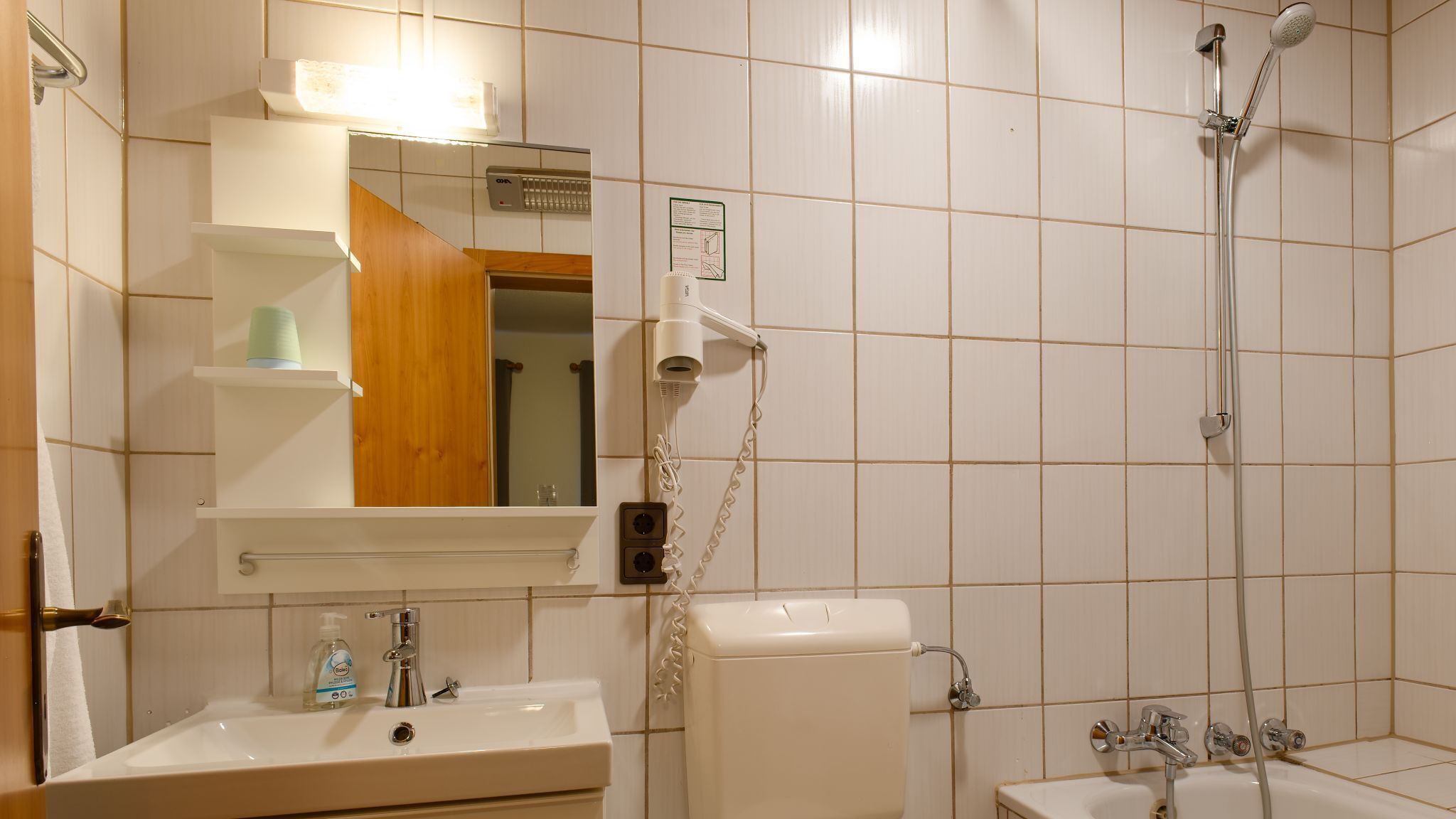 A bathroom with a sink, mirror, toilet, and shower.