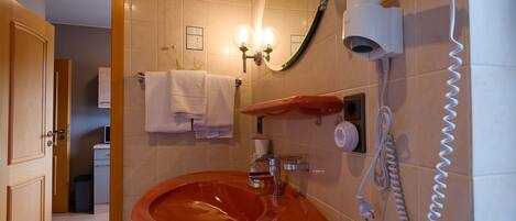 Une salle de bain équipée d’un lavabo, d’un porte-serviettes, d’un miroir et d’un sèche-cheveux.