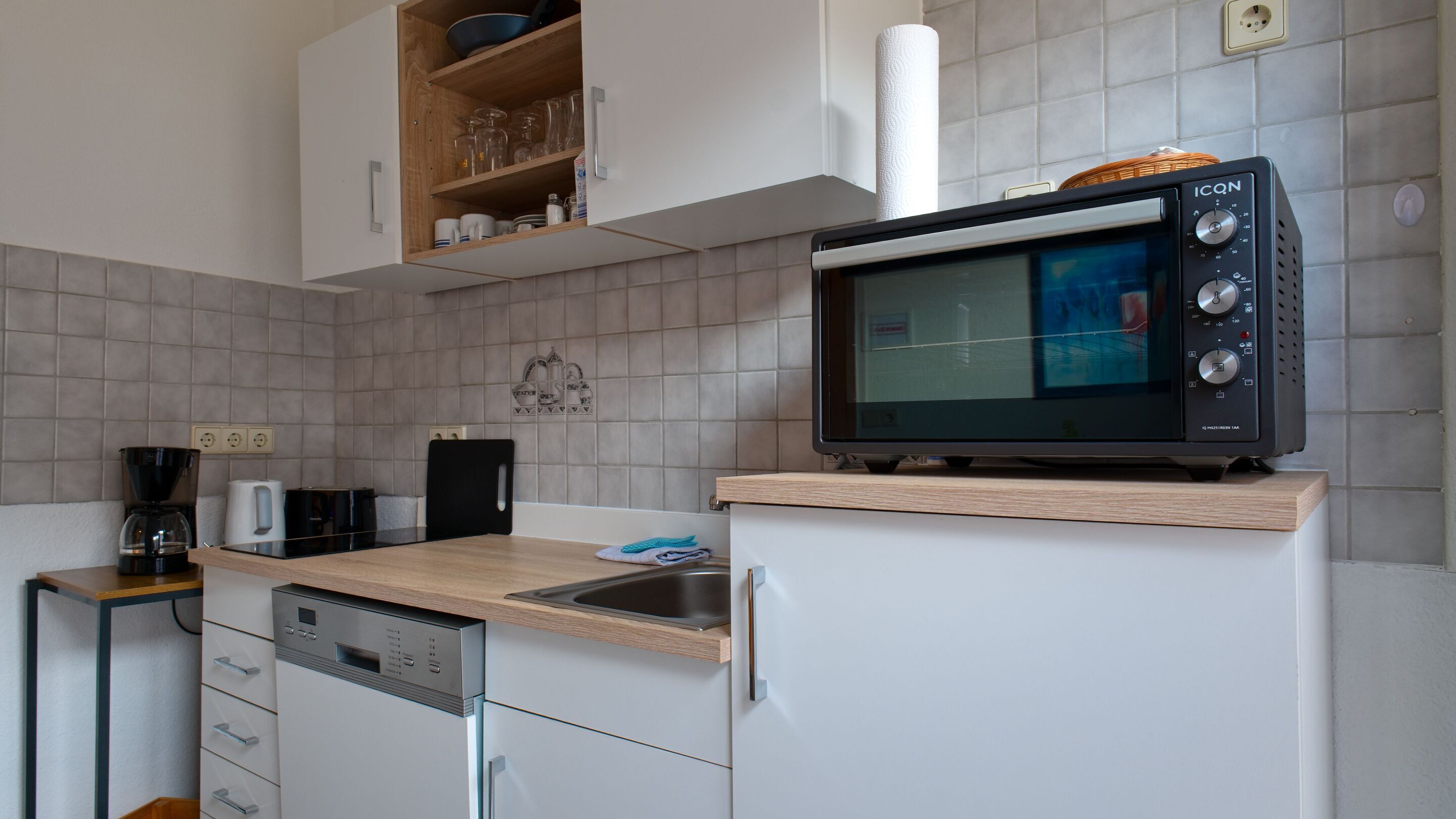 A compact kitchen with a microwave, coffee maker, and dishwasher.