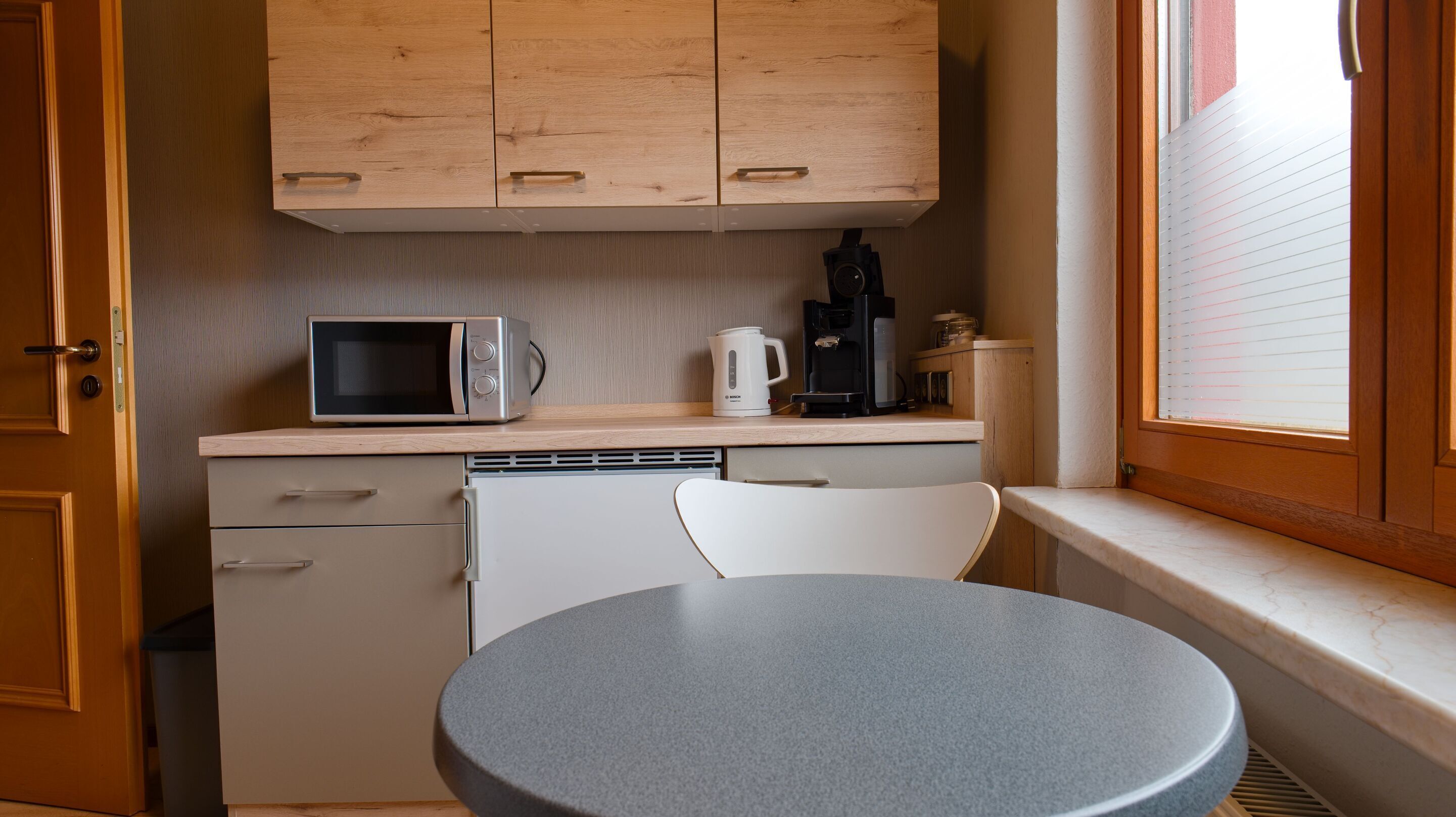 A compact kitchen with a microwave, coffee maker, and a small refrigerator.