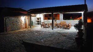 A stone courtyard with outdoor seating and a stone building with a chimney.