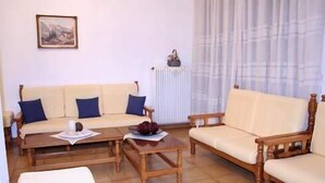 A living room with a beige sofa set, a wooden coffee table, and a white armchair. - Hotel Vicky (Thasos)