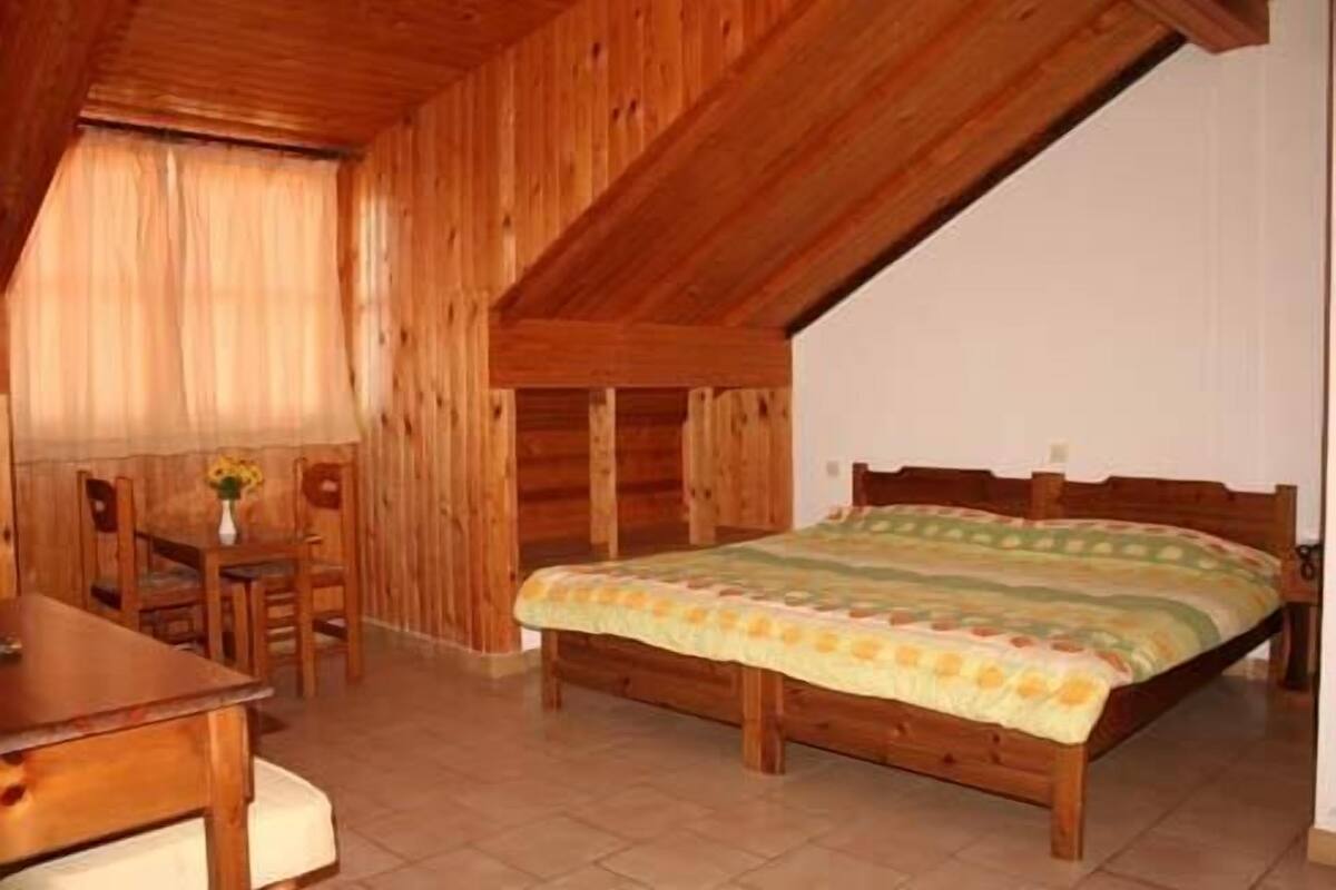 A wooden room with a bed, a table, and a chair.