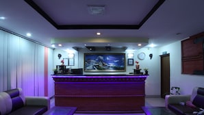 A reception area with a reception desk, two sofas, a coffee table, and a painting on the wall. - Hotel Kathmandu Home Annex (Kathmandu)