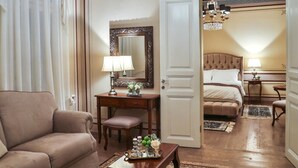 A hotel room with a chandelier, a bed, a sitting area with a sofa and a table, and a mirror on the wall. - 1905 Boutique Hotel (Xanthi)