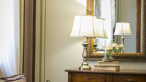A room with a wooden desk, two lamps, a mirror, a cushioned bench, and a chair with a cushion. - 1905 Boutique Hotel (Xanthi)