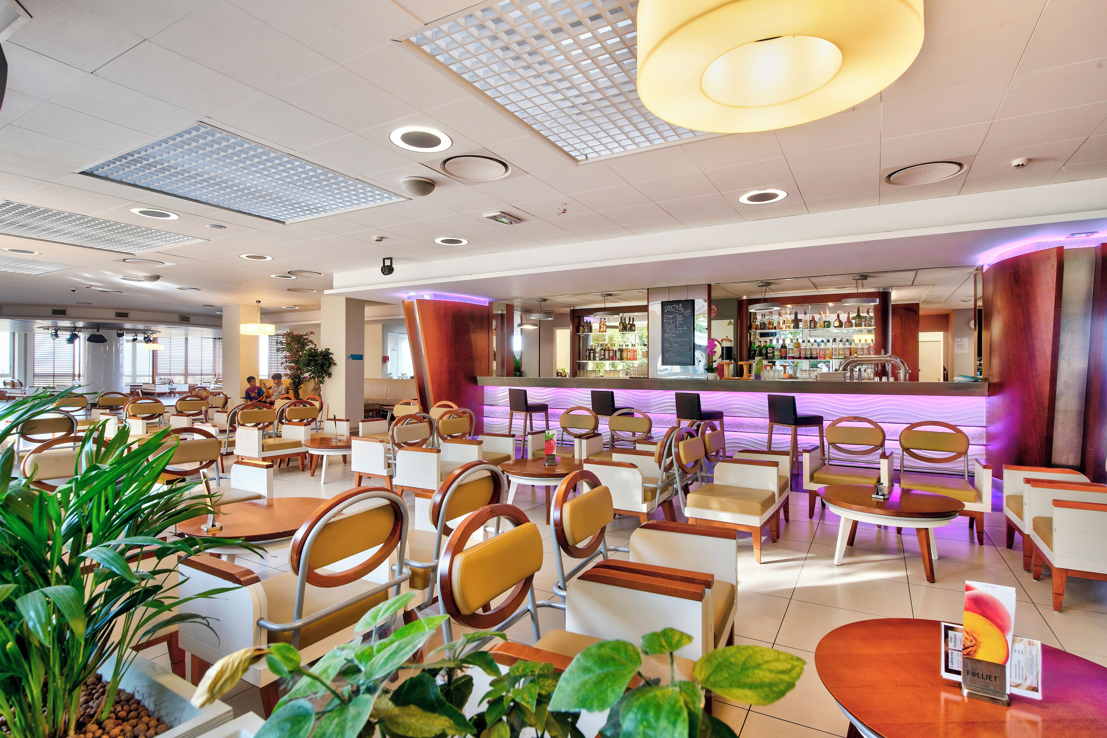 Un'ampia hall dell'hotel con diverse zone relax, un bar e una reception.