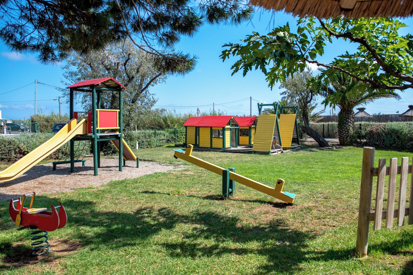 A playground with a slide, swings, and a seesaw.