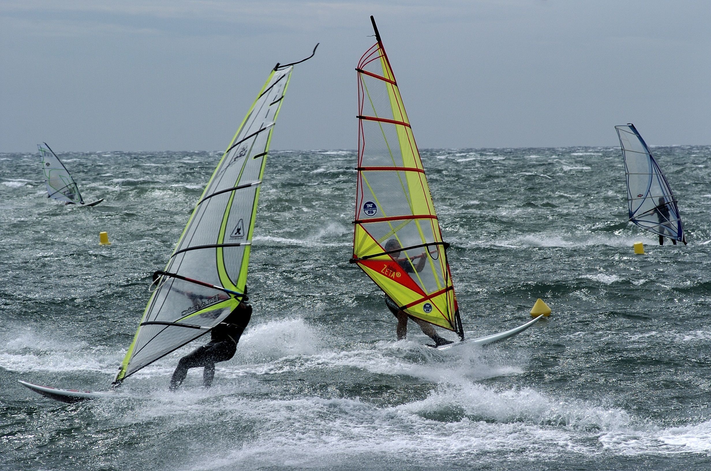 A group of windsurfers on a choppy sea.