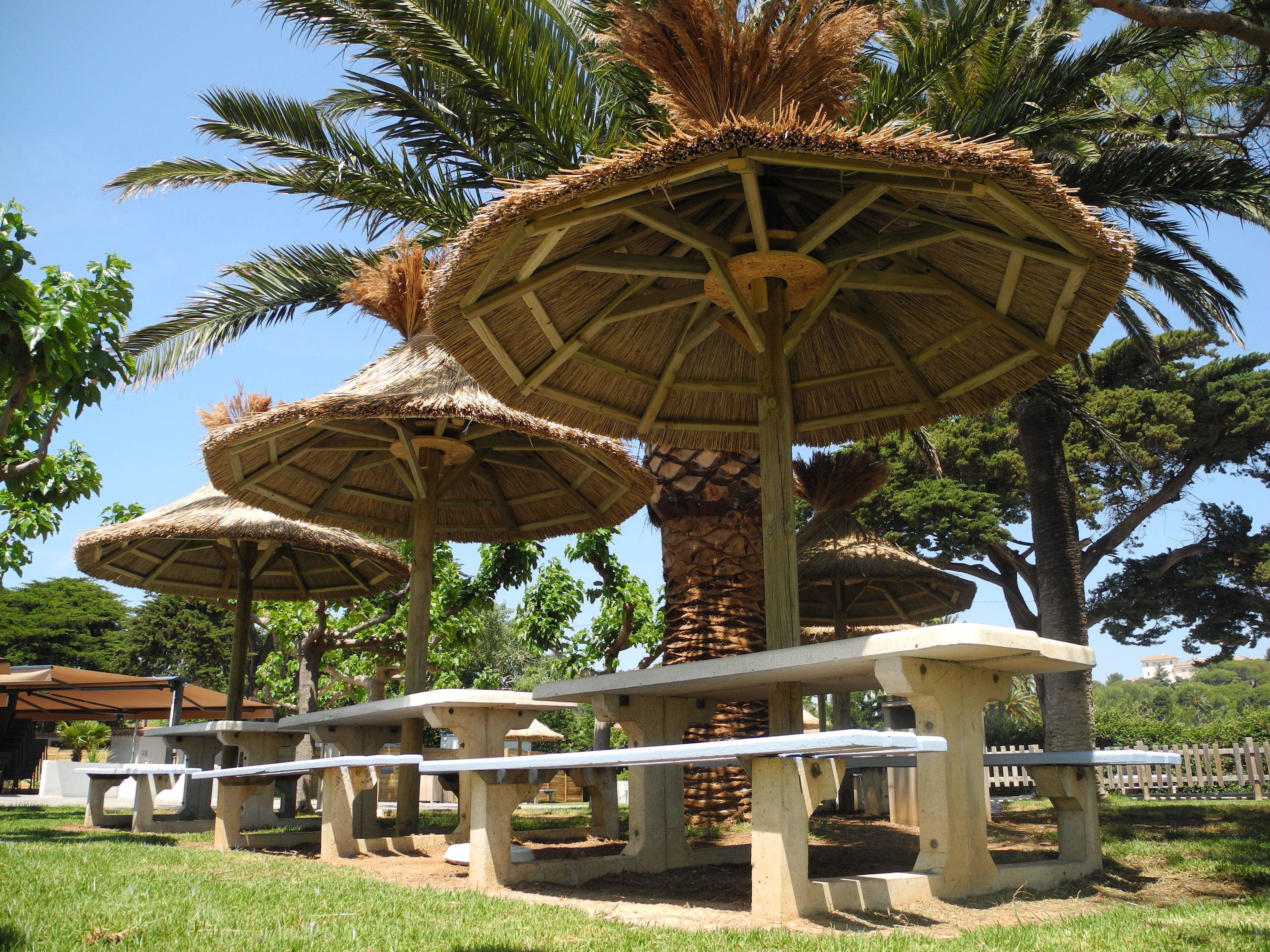 Espaces extérieurs aménagés avec des parasols en chaume et des bancs.
