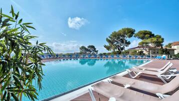 Relax by the pool surrounded by lush greenery and trees.