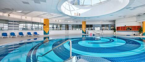 Una piscina techada, sillones reclinables de piscina