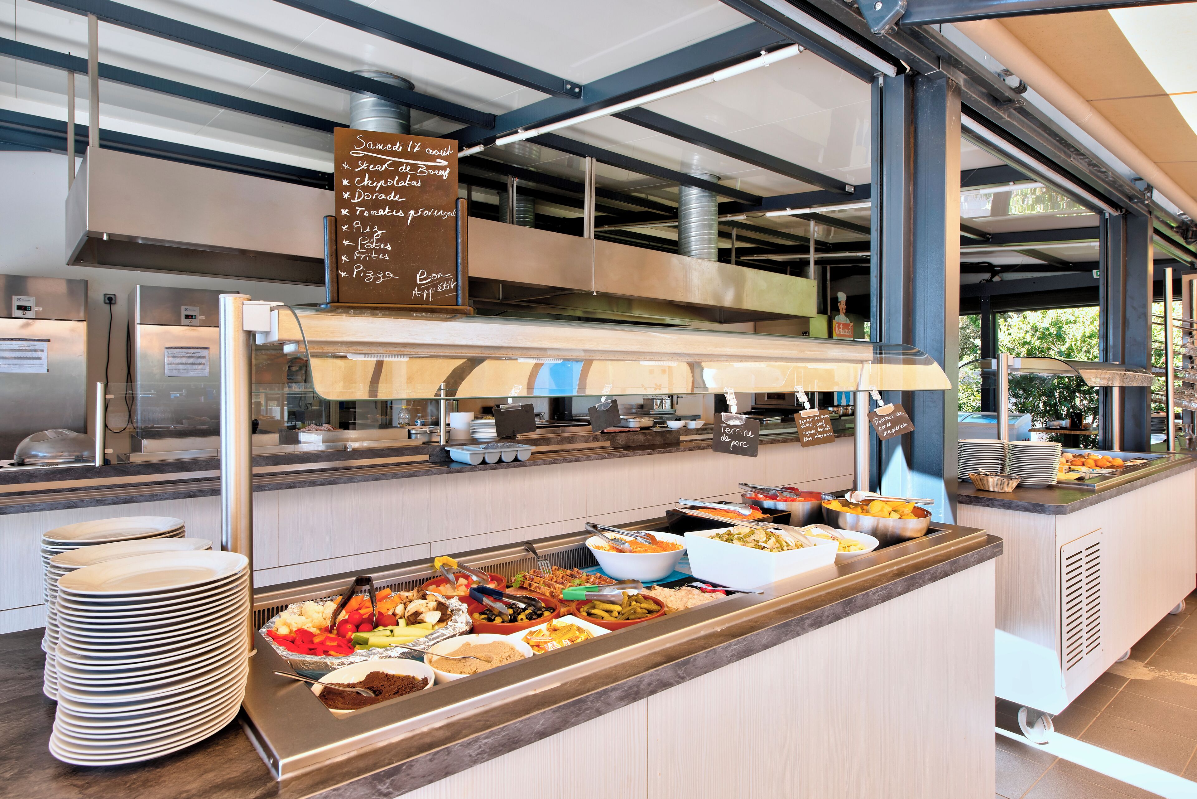 Een buffetgedeelte met diverse gerechtjes en een bord waarop de aanwezige gerechten staan.