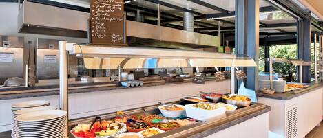 Een buffetgedeelte met diverse gerechtjes en een bord waarop de aanwezige gerechten staan.