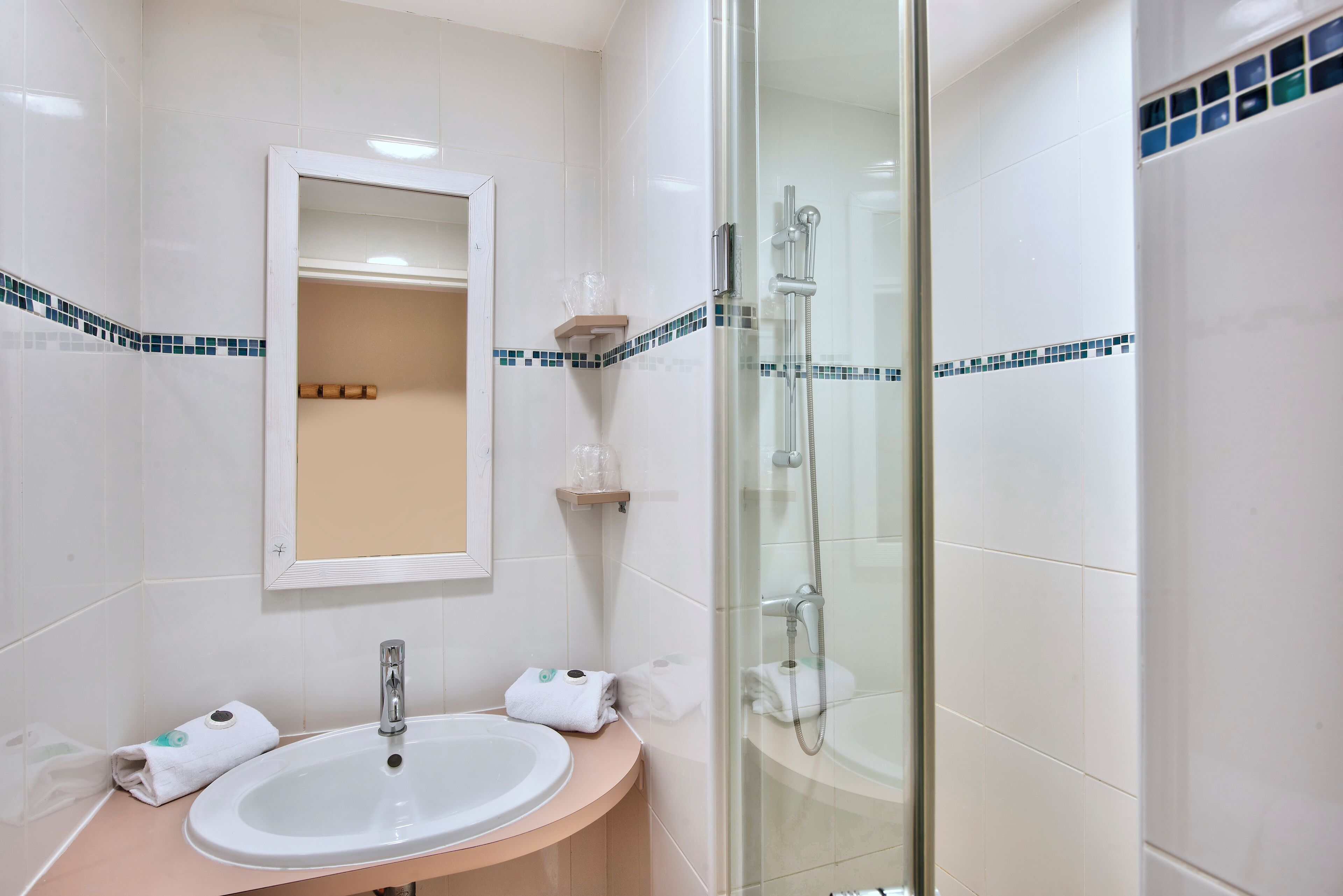 Ein Badezimmer mit Waschbecken, Spiegel und einer Duschkabine.